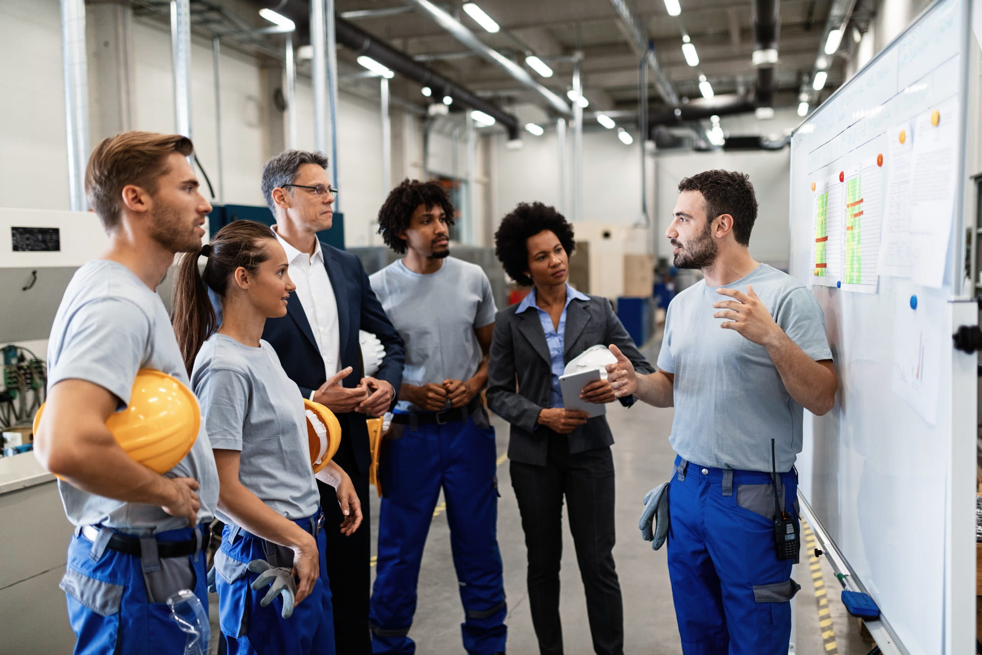 chef d’équipe animant une réunion quotidienne devant un tableau d’indicateurs dans une usine